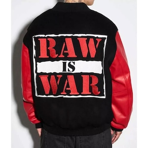 May include: Black varsity jacket with red leather sleeves. The back of the jacket features the words "RAW IS WAR" in red, outlined in white, on a black background. The jacket has a ribbed collar and cuffs.