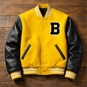 May include: Yellow varsity jacket with black leather sleeves and a white and black striped collar and cuffs. The jacket features a large black and white letter "B" on the chest and two front pockets.