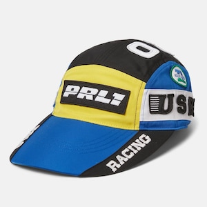 Könnte beinhalten: Eine schwarze, gelbe, blaue und weiße Baseballkappe mit dem Text "PRLI" und "RACING" auf der Vorderseite. Die Kappe hat auch einen kleinen Aufnäher mit dem Text "US" an der Seite.