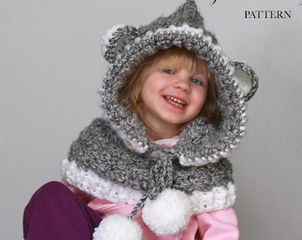 May include: A grey and white crocheted hooded scarf with pom-poms. The hood has bear ears and a white trim. The scarf has a white trim and is worn by a child.
