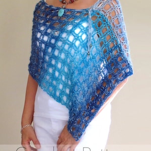 May include: A blue and white crochet shawl with a lacy pattern. The shawl is draped over a person's shoulders and is tied at the neck with a silver bead.