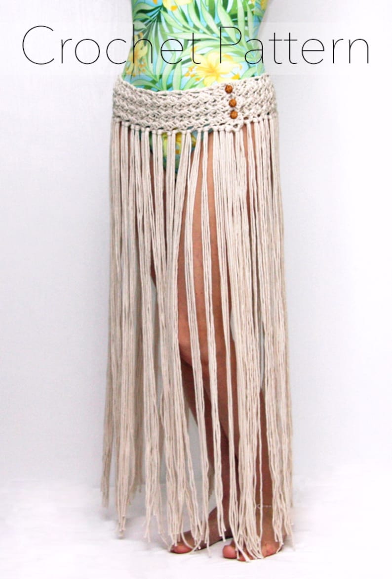 May include: A white crochet skirt with a fringe bottom and a woven waistband. The waistband has three brown wooden beads.