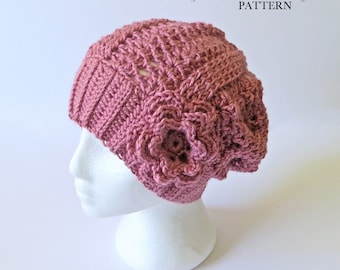 May include: A pink crocheted beanie with a large flower on the side. The beanie is on a white mannequin head. The text "Crystal Bear Designs PATTERN" is at the top of the image.