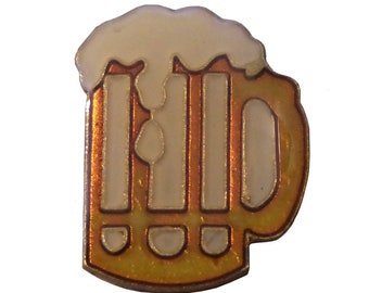 May include: A gold-colored metal pin shaped like a beer stein with a white foam top. The stein has a handle and is filled with a yellow liquid.
