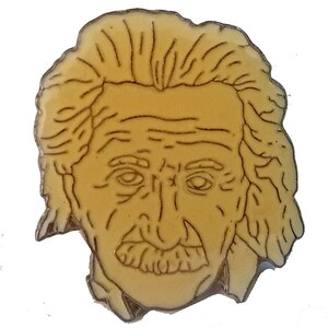 Peut inclure: Une épingle en métal jaune représentant un dessin au trait du visage d'Albert Einstein.