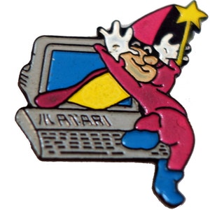 May include: A red and blue cartoon wizard with a yellow star on his hat is sitting on a gray computer with the word "Atari" on the front. The wizard is holding a wand with a yellow star on the top.