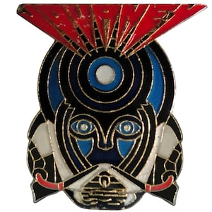 May include: A gold-toned pin with a black and blue stylized face with a red and gold lightning bolt design above it. The pin says "Journey" in red letters.