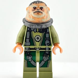 May include: A Lego minifigure of a character with a tan face, orange hands, and a stern expression. The figure wears a green and black uniform with a gray collar. The figure's legs are olive green.