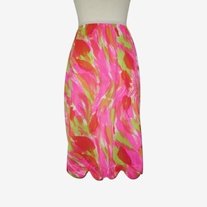 K&ouml;nnte beinhalten: Ein lebendiger, knielanger Rock mit einem farbenfrohen, abstrakten Muster. Das Design zeigt rosa, orange und gr&uuml;ne Striche. Der Rock hat einen gewellten Saum und einen wei&szlig;en Bund. Der Rock ist aus leichtem Stoff gefertigt.
