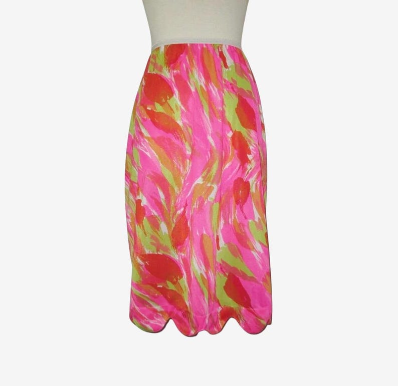 K&ouml;nnte beinhalten: Ein lebendiger, knielanger Rock mit einem farbenfrohen, abstrakten Muster. Das Design zeigt rosa, orange und gr&uuml;ne Striche. Der Rock hat einen gewellten Saum und einen wei&szlig;en Bund. Der Rock ist aus leichtem Stoff gefertigt.