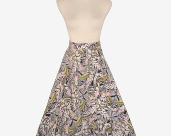 May include: A-line skirt with a floral pattern. The skirt features a black, white, pink, and green leaf and flower design. The skirt is displayed on a mannequin.