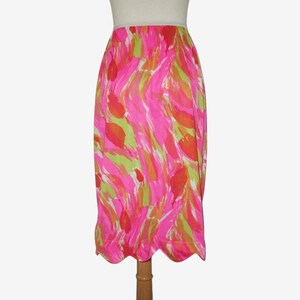 K&ouml;nnte beinhalten: Ein lebendiger, knielanger Rock mit einem farbenfrohen, abstrakten Muster. Das Design zeigt kr&auml;ftige Striche in Pink, Gr&uuml;n und Orange, die einen dynamischen Look erzeugen. Der Rock hat einen wellenf&ouml;rmigen Saum, der dem Design eine elegante Note verleiht. Der Rock ist ca. 76 cm lang.
