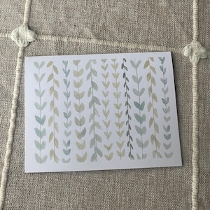 May include: A rectangular art print with a watercolour design of vertical leaf patterns in shades of green, blue, and beige. The artwork is displayed on a neutral-toned, textured surface.