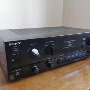 Könnte beinhalten: Schwarzer Sony Stereo-Receiver mit mehreren Knöpfen und Reglern. Auf der Frontplatte steht die Marke "SONY" und der Text "SPONTANEOUS TWIN DRIVE". Der Receiver steht auf einer Holzoberfläche.