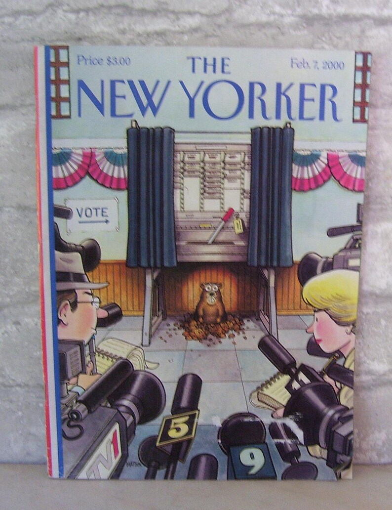 May include: The New Yorker magazine cover from February 7, 2000, features an illustration of a groundhog emerging from a voting booth, surrounded by reporters with microphones and cameras. The groundhog is wearing a brown fur coat and has a surprised expression on its face. The voting booth is decorated with red, white, and blue bunting. The cover also includes the text "The New Yorker" and "Feb. 7, 2000".