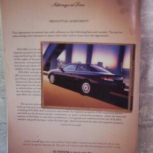 May include: A black and white legal document with the title "Prenuptial Agreement" and the text "SOLARA" repeated multiple times. The document is from the law firm Simon, Bogen & Wells. The document is accompanied by a photo of a black Toyota Solara driving on a road with a bridge in the background. The ad text reads "Let the romance begin with a Camry Solara?" and "If the leather trimmed seats don't sweep you off your feet, the 200 horsepower definitely will. Oh, yeah, and it doesn't make that little whistling sound when it stops."