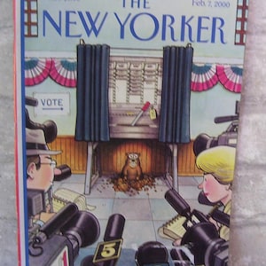 May include: The New Yorker magazine cover from February 7, 2000, features an illustration of a groundhog in a voting booth with reporters and cameras surrounding it. The cover depicts a humorous take on the Groundhog Day tradition.