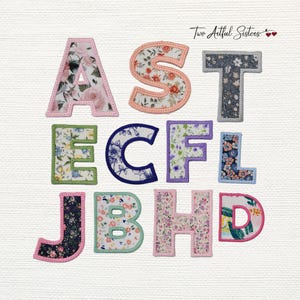 May include: A collection of eleven fabric alphabet letters featuring various floral and botanical patterns. Each letter is outlined with a stitched border in a coordinating thread color. The letters include A, S, T, E, C, F, L, J, B, H, and D.