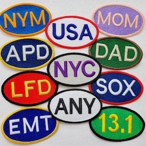 May include: A collection of embroidered oval patches in various colors. Each patch features text, including "NYM", "USA", "MOM", "APD", "NYC", "DAD", "LFD", "SOX", "EMT", "ANY", and "13.1". The patches have a stitched border.