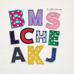 May include: A collection of colorful, polka-dotted fabric letters in various colors, including pink, purple, red, green, yellow, and blue. Each letter has a white border and is arranged on a white background. The letters spell out "BMS LCHE AKJ".