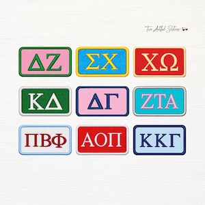 May include: A collection of nine rectangular embroidered patches featuring Greek letters in various color combinations, including pink, green, blue, red, and white. Each patch has a distinct border color and text, with the logo Two Artful Sisters visible.
