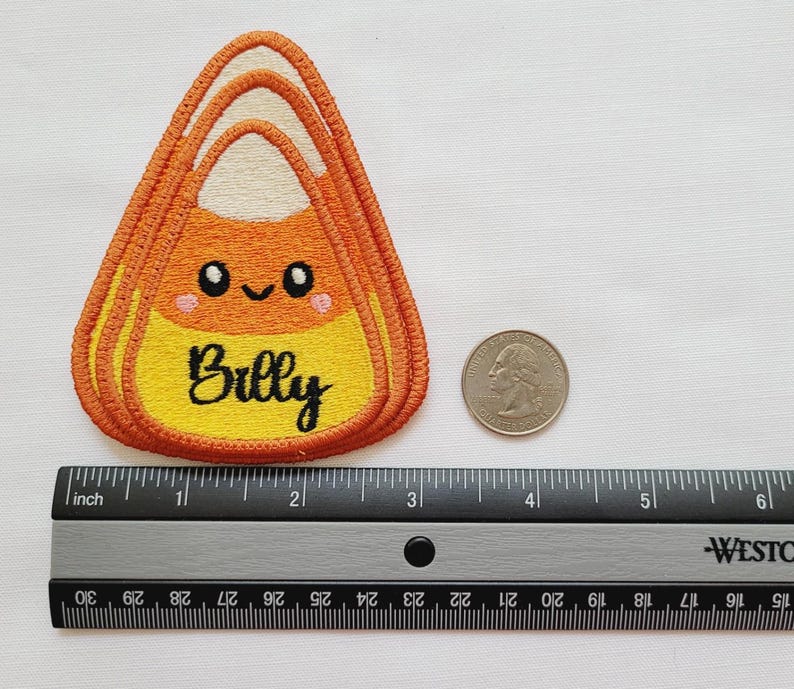 Peut inclure: &Eacute;cusson brod&eacute; en forme de bonbon de ma&iuml;s avec le nom "Billy" en &eacute;criture noire. Le patch pr&eacute;sente un visage souriant et mesure environ 7,6 cm de large. Une r&egrave;gle et une pi&egrave;ce de monnaie sont &agrave; c&ocirc;t&eacute; du patch pour la r&eacute;f&eacute;rence de taille.