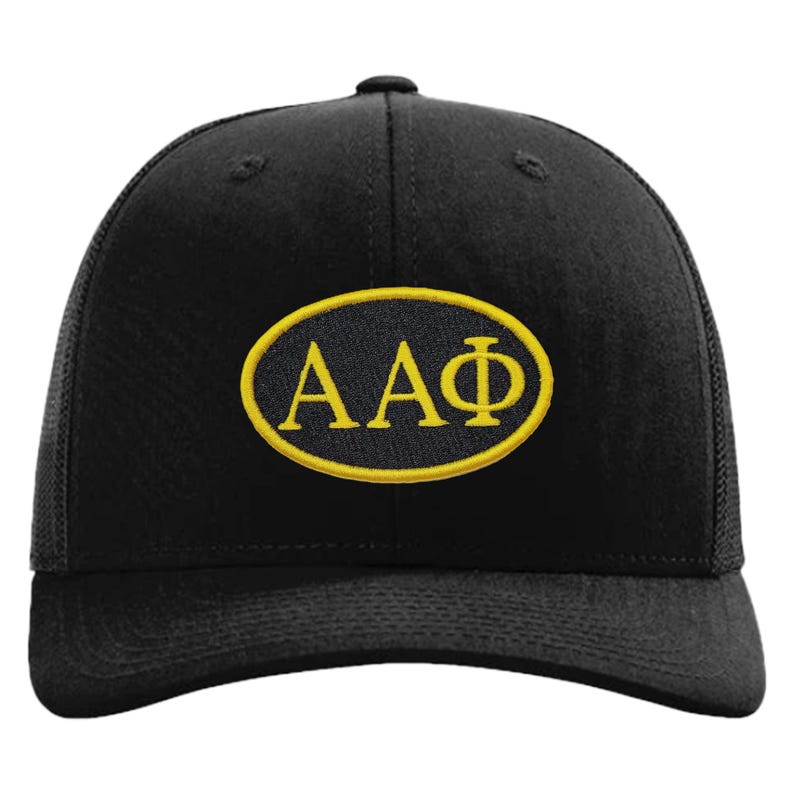 May include: Black baseball cap with a mesh back and a curved peak. The cap has a yellow embroidered oval patch with the Greek letters &Alpha;&Alpha;&Phi;.