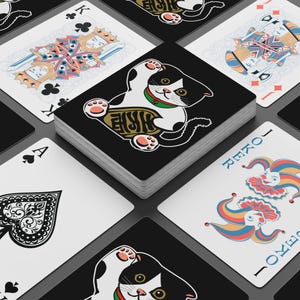 May include: A deck of playing cards featuring a black and white cat design on the card backs. The deck includes face cards, a Joker, and other suits. The cat design has a green collar and the text "Eryk".