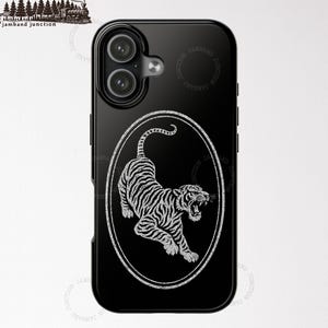 May include: Black iPhone 17 case featuring a white illustration of a tiger inside an oval frame. The tiger is depicted with detailed stripes and an open mouth. The case has a glossy finish. The text "IPHONE 17" is at the bottom.