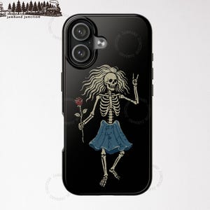 May include: Black iPhone 17 case featuring a skeleton illustration with long hair, a blue skirt, and a red rose. The skeleton is giving a peace sign. The case has a glossy finish.