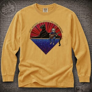 May include: Mustard yellow long-sleeve shirt with a graphic featuring a black cat, a musician playing a guitar, and the text "Just Another Cat Beneath the Stars Tonight." The graphic has red, blue, and purple accents.