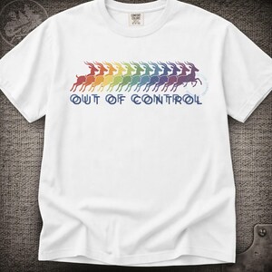 May include: A white short-sleeved t-shirt featuring a graphic of a row of leaping gazelles in a rainbow colour gradient. Below the gazelles, the text "OUT OF CONTROL" is printed in a dark blue sans-serif font. The shirt has a crew neckline.