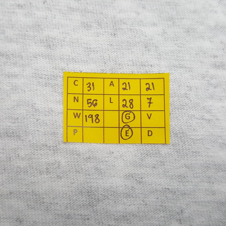 May include: A close-up of a yellow sticky note with black text and numbers. The note is divided into boxes with the letters C, N, W, P, A, L, G, E, V, and D. The numbers 31, 56, and 198 are visible.