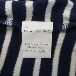 May include: Close-up of a navy blue and white striped fabric with a tag. The tag reads "NO. B J~T 39-007" and "Fabriqu&eacute; au Japon Made in Japan Y's bis Co.,Ltd."