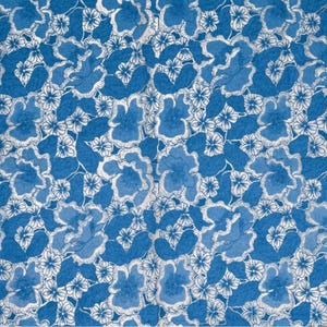 Peut inclure: Un tissu présentant un motif floral répétitif dans des tons de bleu et de blanc. Le design se compose de fleurs et de feuilles de différentes tailles, dessinées dans un style esquissé avec des contours blancs sur un fond bleu uni.