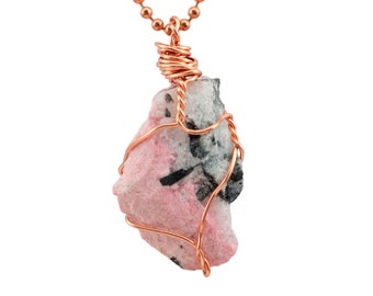May include: A pink and white stone pendant wrapped in copper wire, hanging from a copper chain.