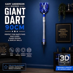 May include: A 90cm long Gary Anderson inspired giant dart wall display. The dart features a blue and white flight with gold text, a white shaft with the Unicorn logo, and a silver metallic barrel. The text on the wall reads Giant Dart 90cm.