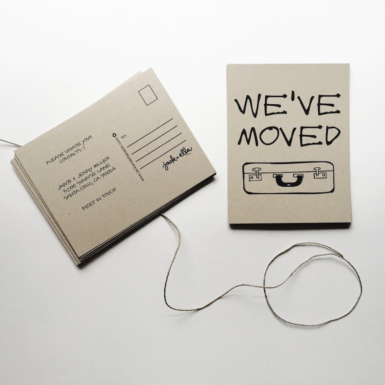 May include: A stack of brown postcards with the text "PLEASE UPDATE YOUR CONTACTS" and "WE'VE MOVED" with a suitcase graphic. The text "jack-ella" is printed on the postcard.