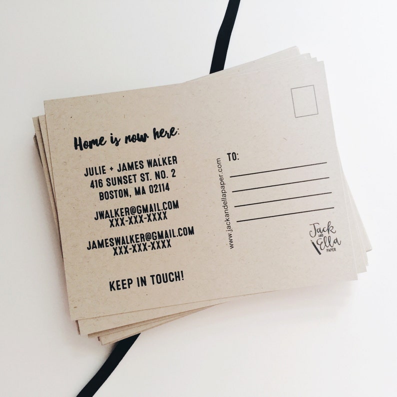 May include: A brown kraft paper postcard with the text "Home is now here:" and contact information for Julie and James Walker. The postcard also includes the website address "www.jackandellapaper.com" and the text "TO:" with a blank space for writing. The bottom right corner of the postcard has a logo for "Jack and Ella Paper."