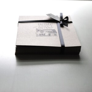 May include: A stack of brown paper cards tied with a black ribbon. The cards have a black and white illustration of a house with the text "Home Sweet Home" printed on the front.