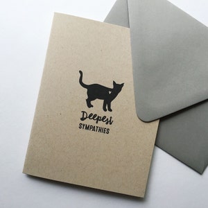 May include: A brown card with a black silhouette of a cat with a heart on its chest. The card says "Deepest Sympathies" in black text.