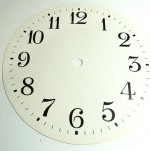 Peut inclure: Un cadran de montre de couleur crème avec des chiffres noirs et des marqueurs de minutes. Les chiffres de 1 à 12 sont espacés uniformément sur le cadran circulaire. Un petit trou est centré au milieu.