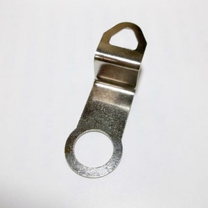 May include: Silver metal clock hand with a hole in the center and a hook on the top.