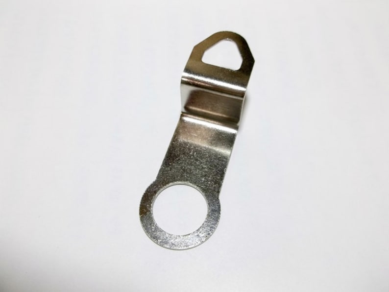 May include: Silver metal clock hand with a hole in the center and a hook on the top.