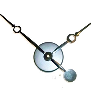 May include: Black clock hands with a black metal center piece. The hands are designed with a decorative circle at the end of each hand.
