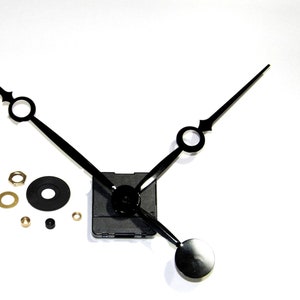 Könnte beinhalten: Schwarzes Uhrwerk-Set mit Zeigern und Montagezubehör. Das Set enthält ein schwarzes Zifferblatt, Stunden-, Minuten- und Sekundenzeiger, eine Montagenuss und eine Unterlegscheibe.