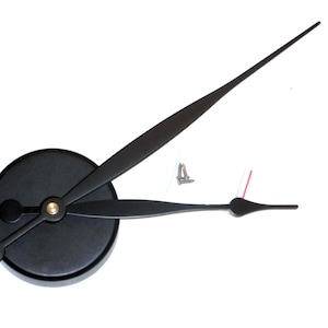 Könnte beinhalten: Schwarze Uhrzeiger mit goldener Mitte, einem runden schwarzen Sockel und zwei silbernen Schrauben. Die Zeiger sind für eine Uhr mit einem Durchmesser von 30 cm oder größer ausgelegt.