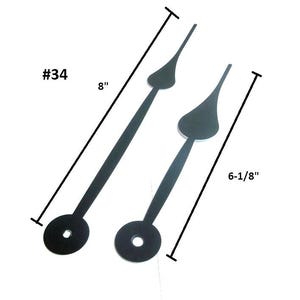 May include: Two black clock hands. The longer hand is 8 inches long, and the shorter hand is 6-1/8 inches long. Each hand has a circular base with a hole and a pointed tip. The text "#34" is in the upper left corner.