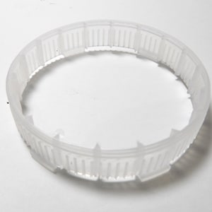 Puede incluir: Un anillo de plástico blanco con una serie de pequeñas crestas espaciadas uniformemente alrededor de la circunferencia.