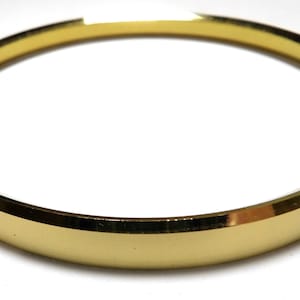 May include: A gold-colored bangle bracelet with a smooth, polished finish.